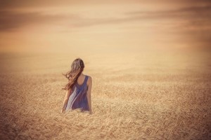 sad-girl-in-purple-dress-walking-through-wheat-field-at-sunset